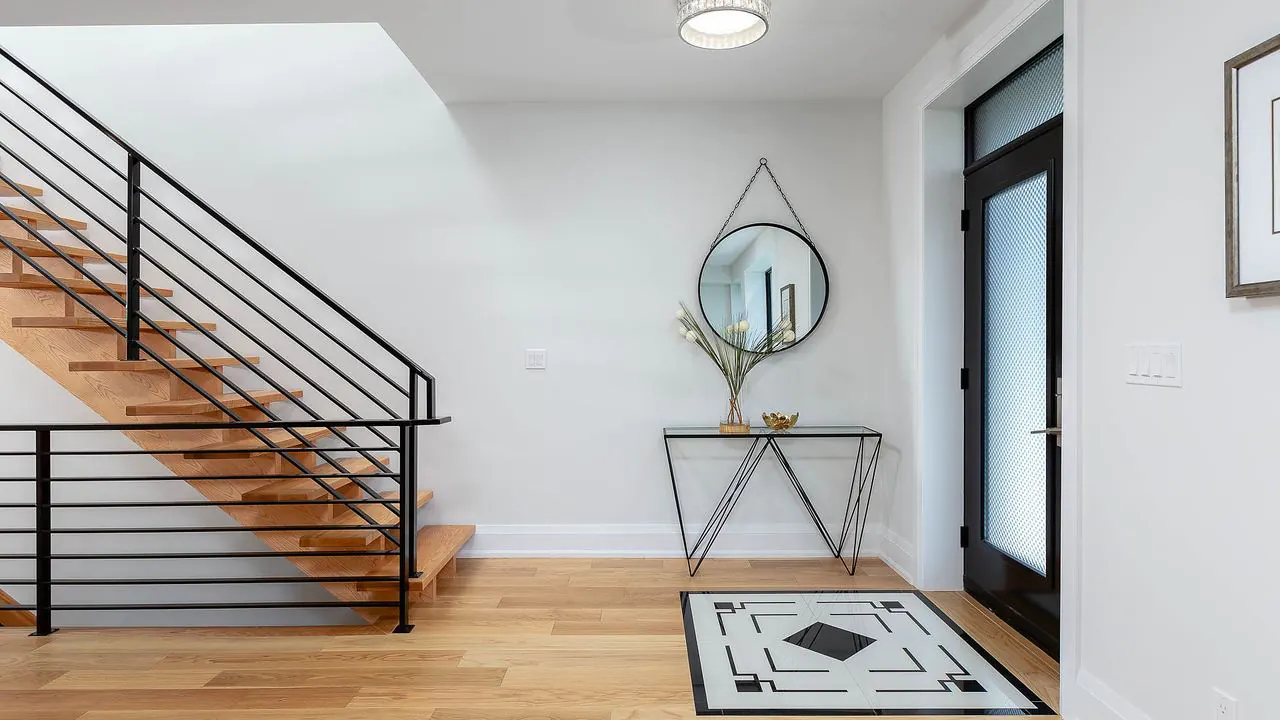 Entry foyer with wood staircase and black metal railing