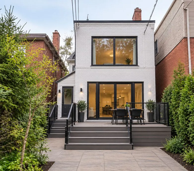 Rear elevation of the Constance renovation with white cladding, black-framed windows and a new raised deck